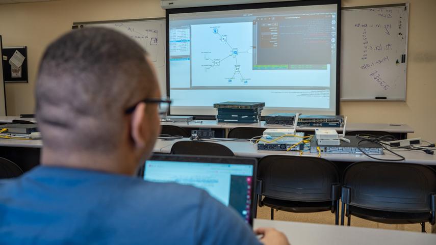 cybersecurity student on laptop at lecture