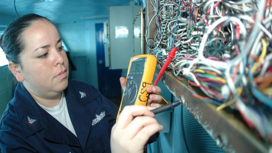 electrician using multimeter and working with many wires